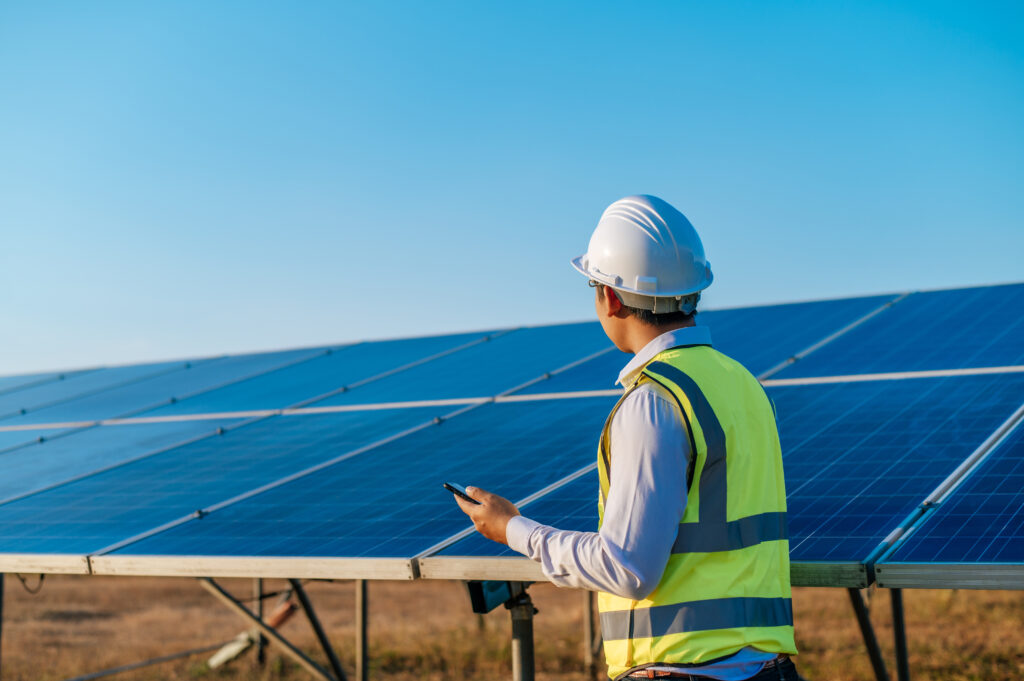 Young engineer use smartphone while working at solar farm